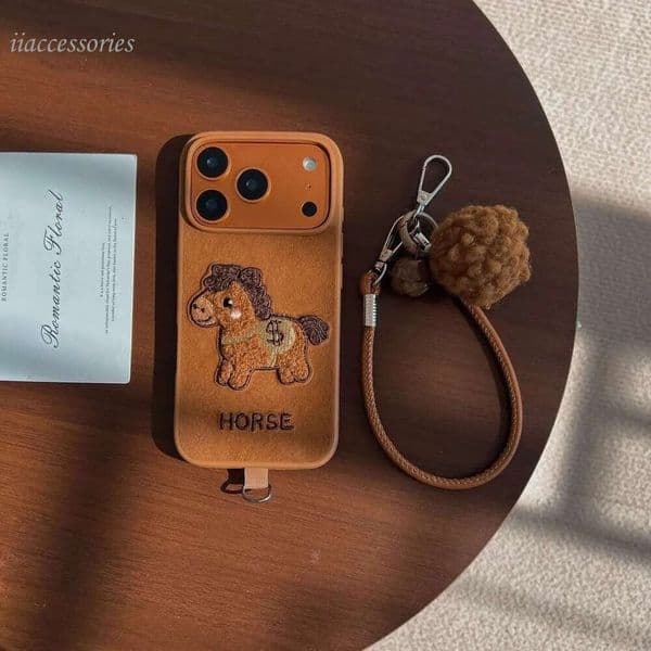 IPhone Embroidered Money Pony Apple 17 Pro Max phone case for iPhone 16/15/14 with Hand Strap and Pom-Pom Soft Case