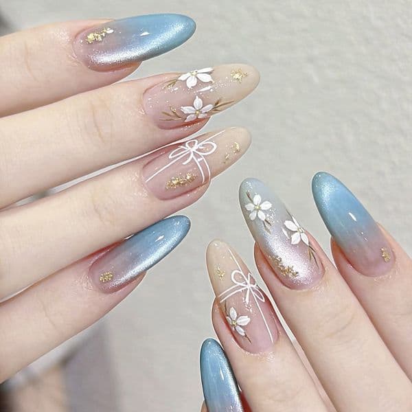 Icy blue-pink gradient manicure with hand-painted white flowers gold foil accents, versatile for everyday wear, detachable and wearable nails