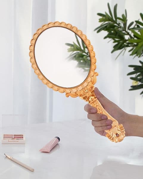 A silver handheld mirror for dressing up, holding it in his hand, using a double mirror as a mirror, and wearing a pair of clothes with a small figure line.
